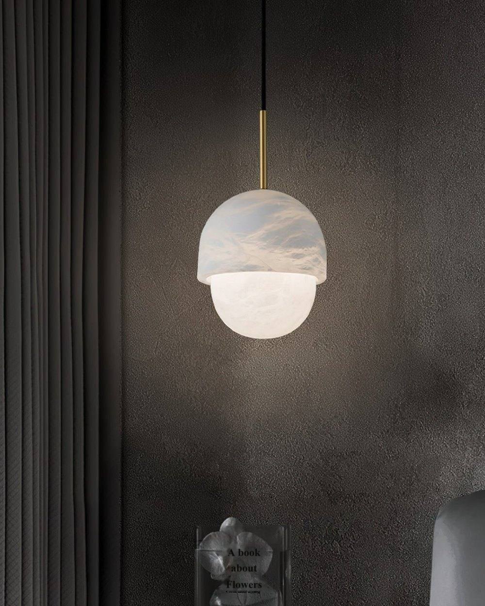 An alabaster pendant glowing against a dark plaster wall